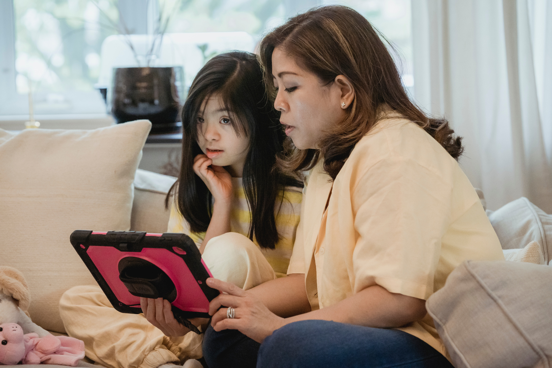 Woman in Yellow Shirt Holding Pink and Black Digital Tablet