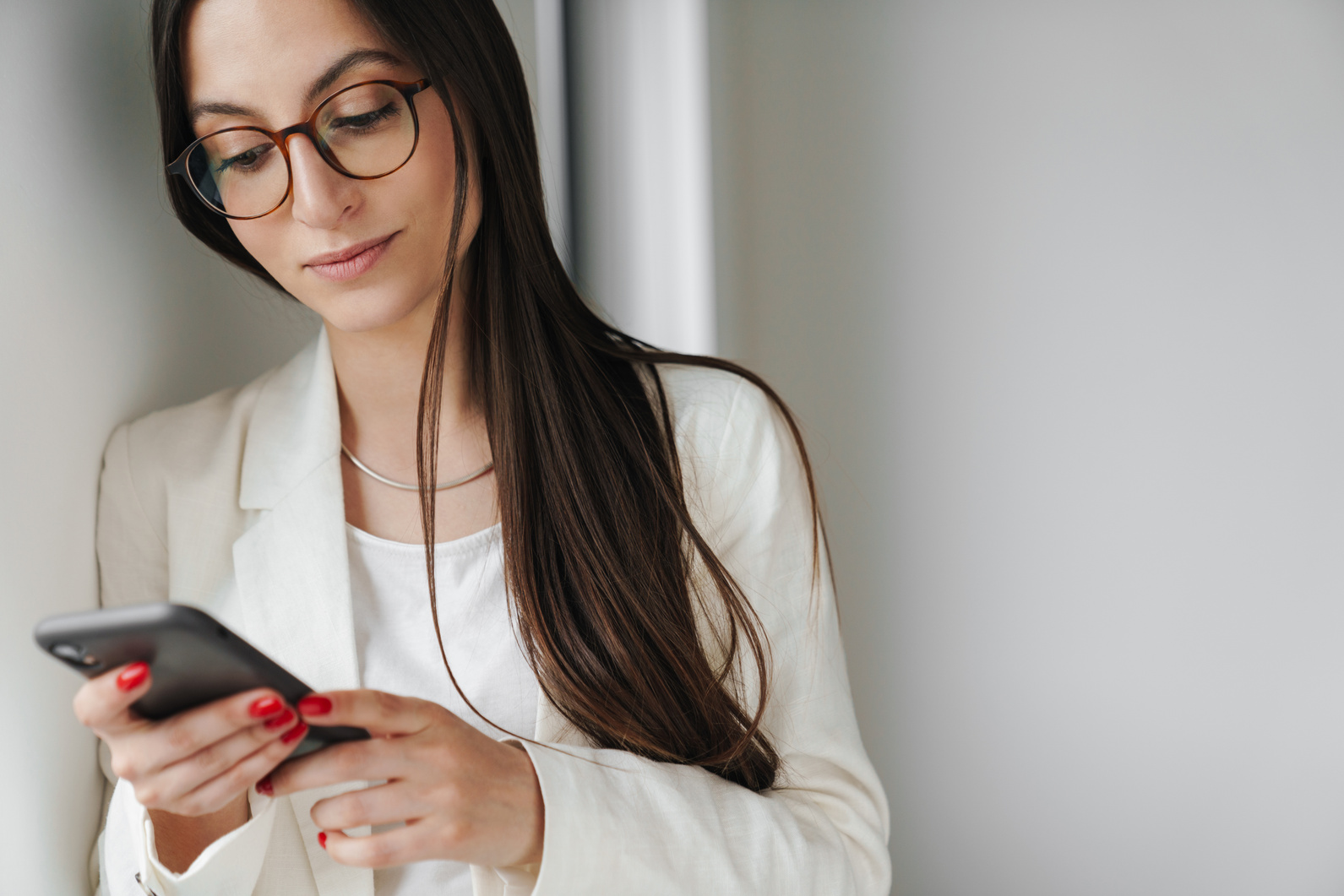 Photo of Pleased Businesswoman Using Mobile Phone While Leaning on Wall